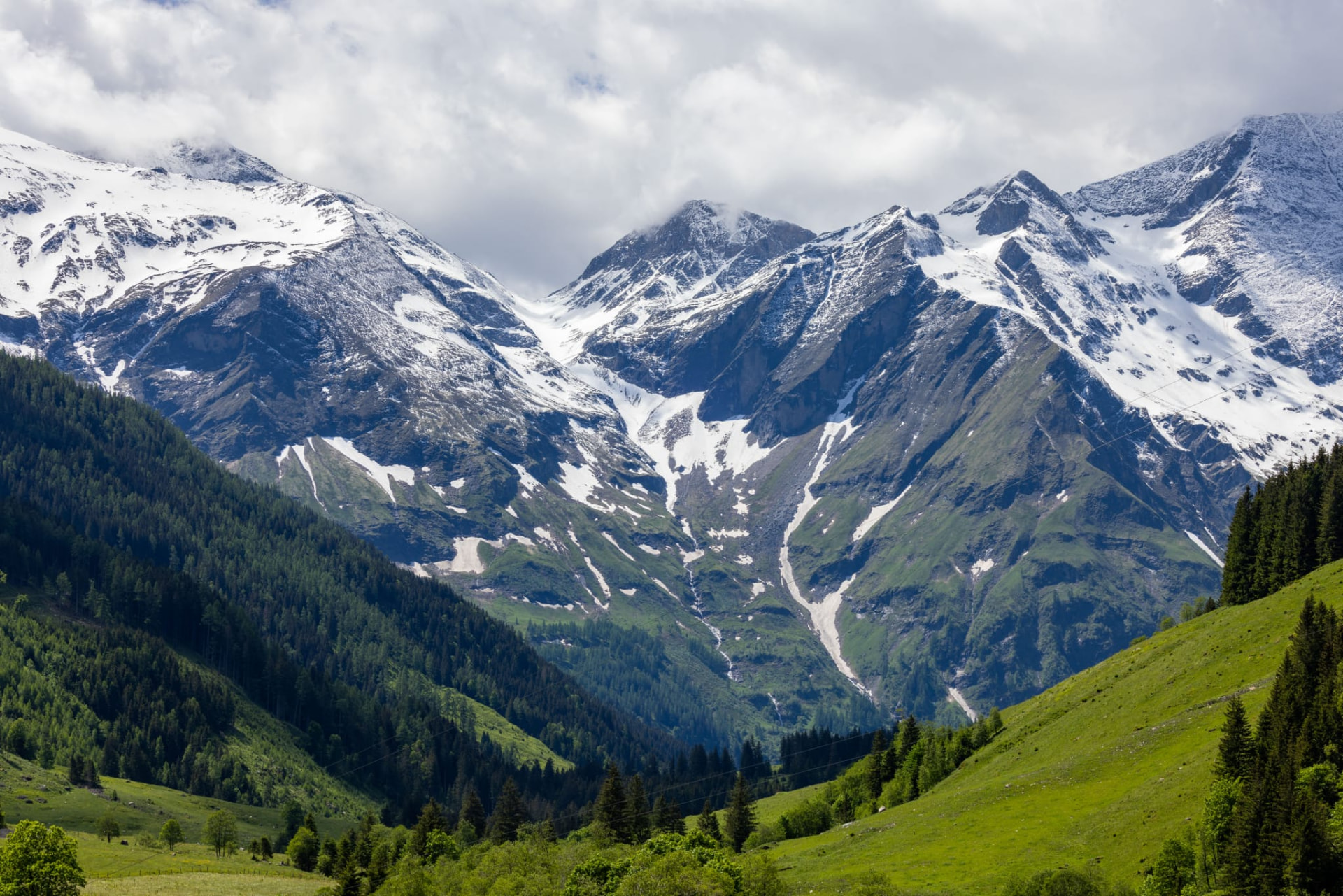 Snow-covered mountain range above green slopes